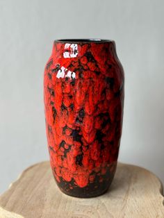 a red and black vase sitting on top of a wooden table