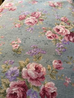 an upholstered table cloth with pink and purple flowers on light blue groundcloth