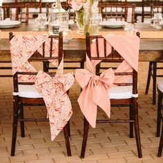 two chairs with bows tied to them are sitting at a table