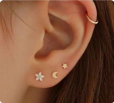 a woman's ear with two small stars and a moon on the back of it