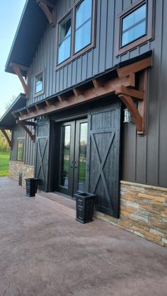 the front entrance to a large house with black doors and brown trim on the windows