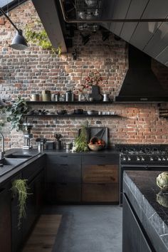 an industrial kitchen with exposed brick walls and black counter tops, along with wooden flooring