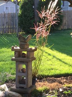 a stone lantern sitting on top of a grass covered field next to a tall plant