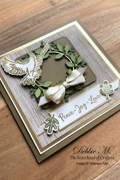 a close up of a card on a wooden table with a bird and wreath design