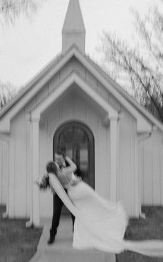 a bride and groom are dancing in front of a church