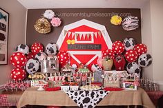 a table topped with lots of red and white balloons next to a farm animal theme