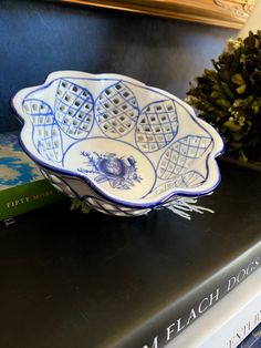 a blue and white bowl sitting on top of a table next to a stack of books