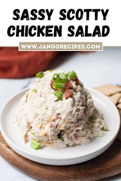 a white plate topped with chicken salad next to crackers