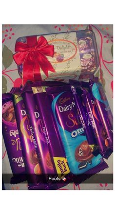 six dairy milk chocolate bars wrapped in red ribbon and tied with a bow on a bed