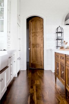 a large wooden door in a white kitchen