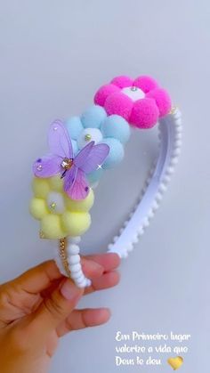 a hand is holding a hair band with flowers and butterflies on the top of it