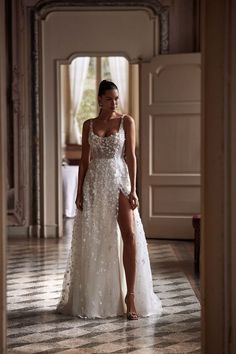 a woman in a white dress walking down a hallway