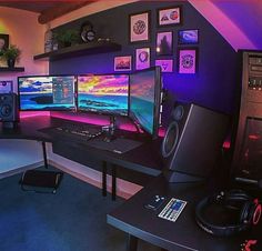 a computer desk with two monitors, speakers and a laptop on it in front of a purple wall