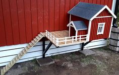 a dog house built into the side of a red building with stairs leading up to it