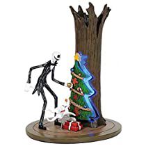 a figurine is standing next to a christmas tree with presents under it on a wooden base