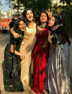 four women posing for the camera with their arms around each other and one woman holding her hand up