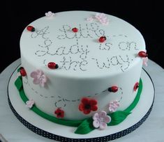 a white cake with flowers and ladybugs on the top is sitting on a table