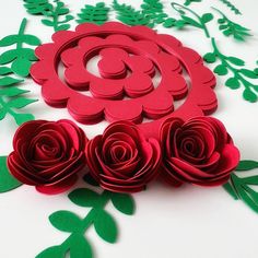 paper flowers and leaves on a white surface