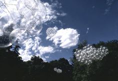 some clear balloons floating in the air on a sunny day with blue sky and clouds