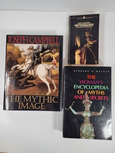 three books are sitting on the wall next to each other, one is titled the woman's encyclopedia of mystic and the other is written by joseph campbell