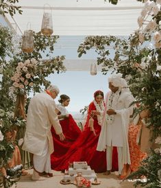 a group of people standing next to each other in front of flowers and greenery