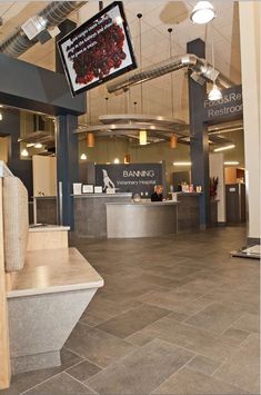 an office lobby with stone flooring and large television screens above the desks on the ceiling