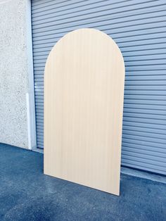 a large wooden arch sitting in front of a garage door next to a closed building