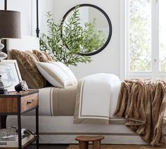 a bedroom with a bed, dresser and mirror in it's corner next to a window