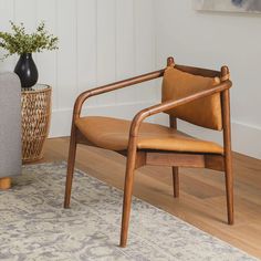 a wooden chair sitting on top of a hard wood floor next to a potted plant