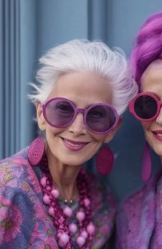 two older women with pink hair and purple sunglasses are posing for the camera while wearing matching outfits