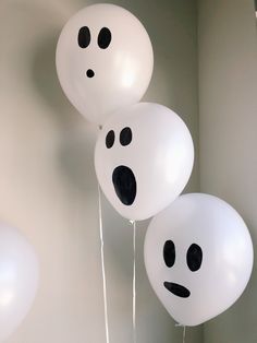 three white balloons with black faces on them