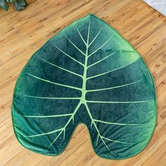 a large green leaf shaped pillow sitting on top of a wooden floor