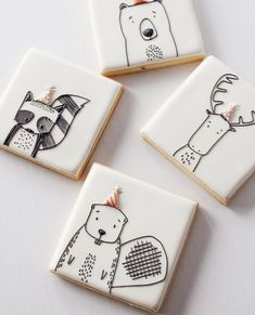 four decorated cookies with animals on them sitting on a white counter top next to each other