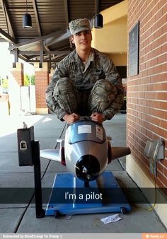 a man in uniform sitting on top of an air force jet next to a brick building