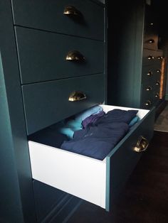 an empty drawer in the middle of a room with blue sheets and pillows on it