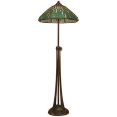 a floor lamp with a green glass shade on the top and an iron pole base