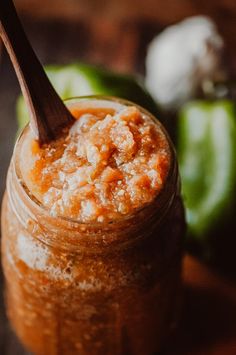 a jar filled with food sitting on top of a wooden table next to green peppers