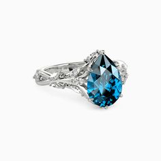 a blue diamond ring with white diamonds on the sides and an intricate band around it