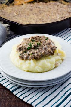 a white plate topped with mashed potatoes and gravy next to a casserole dish