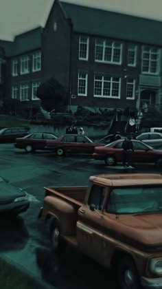 an old pickup truck is parked in front of a large brick building with many windows