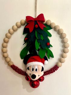 a christmas ornament hanging from the side of a wall next to a beaded necklace