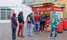 people standing in line at a hot dog stand