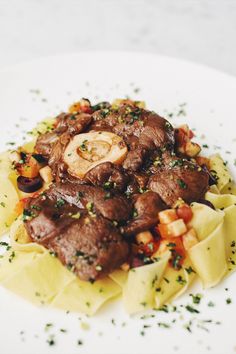 a white plate topped with pasta and meat