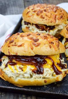 two cheesy chicken sandwiches with ketchup and mayonnaise on a black tray