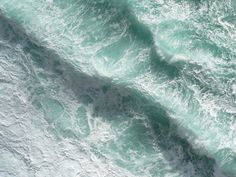 an aerial view of the ocean waves and surfers on their surfboards in the water