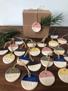 small ceramic ornaments are tied with twine and placed on a table next to a gift box