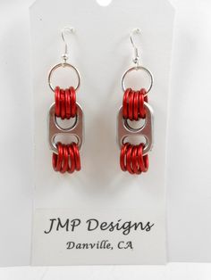 red and silver earrings are displayed on a white display stand with the name jmp designs danville, ca