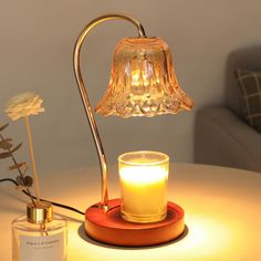 a table with a glass candle and a lamp on it next to a bottle of perfume