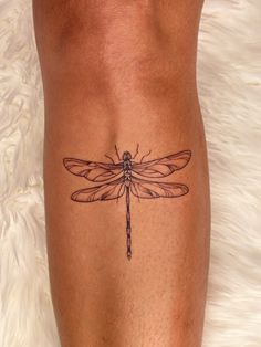 a woman's leg with a tattoo of a dragonfly on it