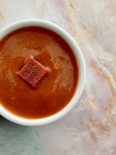 a white bowl filled with soup on top of a marble counter next to a green napkin